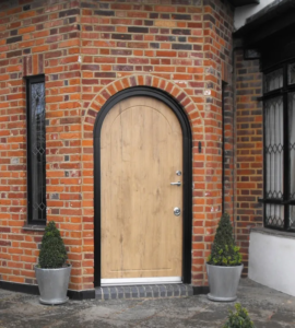 Arched wood-style residential security door in a brick entry